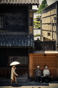Two elderly women watch a young lady walk by