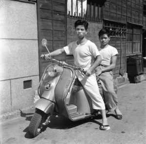 Two boys sit on a vespa