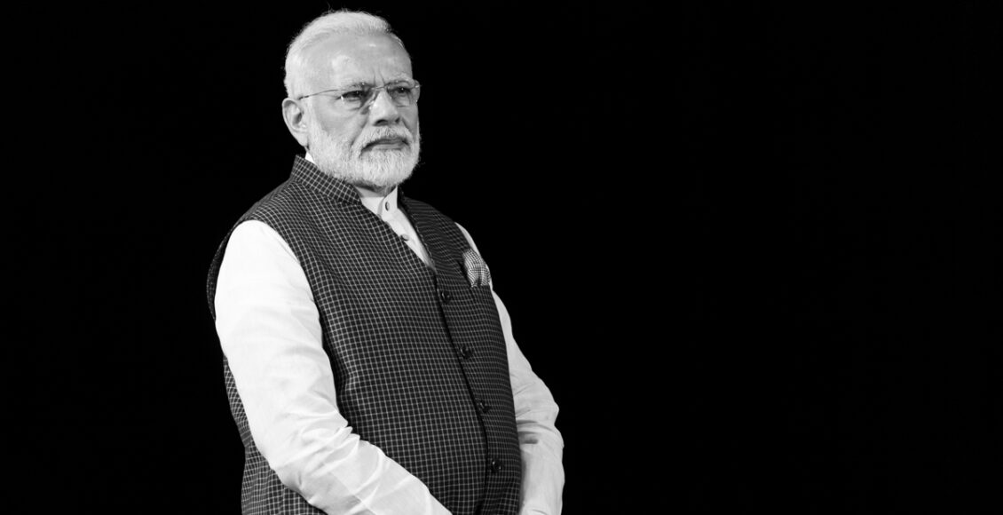 Prime Minister Narendra Modi standing against a black background